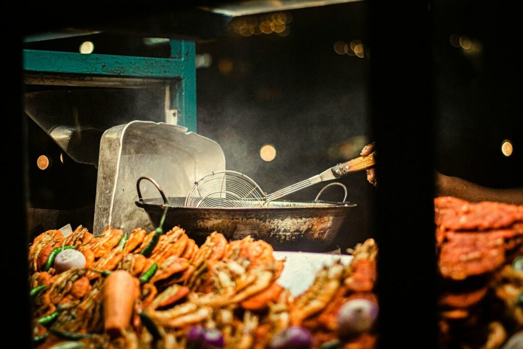 Street vendor preparing Kottu Roti on a hot griddle with metal blades in Colombo at night