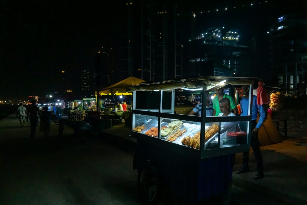 Street vendor preparing Kottu Roti on a hot griddle with metal blades in Colombo at night — supporting travel image 2